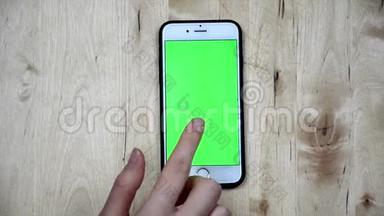 擦拭智能手机屏幕。 顶视图用手指触摸手机，绿色屏幕，阿尔法频道手机屏幕